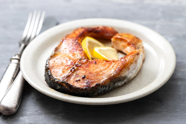 Salmón frito con limón en el plato de cerámica