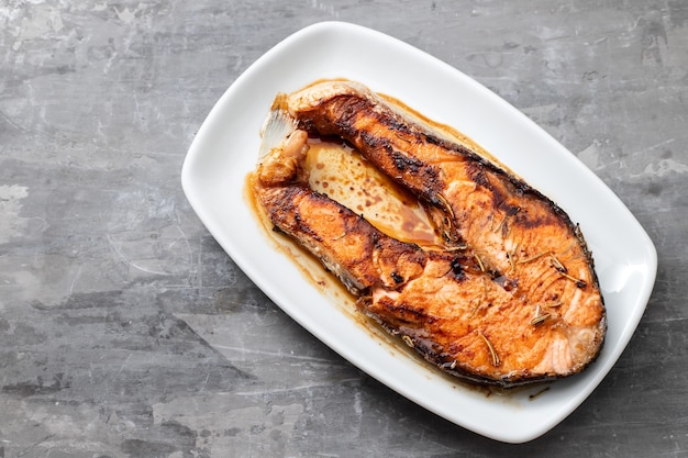 Salmón frito en un plato blanco sobre fondo de cerámica