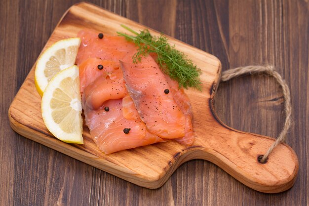 Salmón con limón y pimienta negra sobre tabla de madera sobre madera marrón