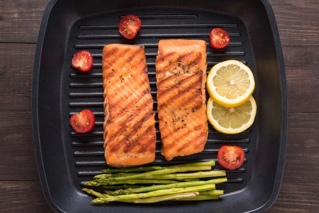 Salmón a la parrilla cocinado barbacoa en una sartén sobre mesa de madera