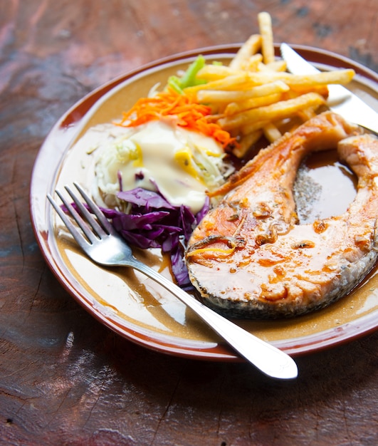 Salmón a la parrilla, ensalada y condimentos en madera