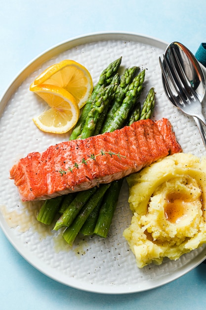 Salmón a la parrilla con espárragos frescos y puré de papas en un plato. comida sana en la mesa