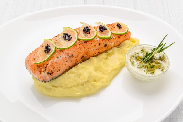 Salmón a la parrilla, papas hervidas y verduras en un plato blanco