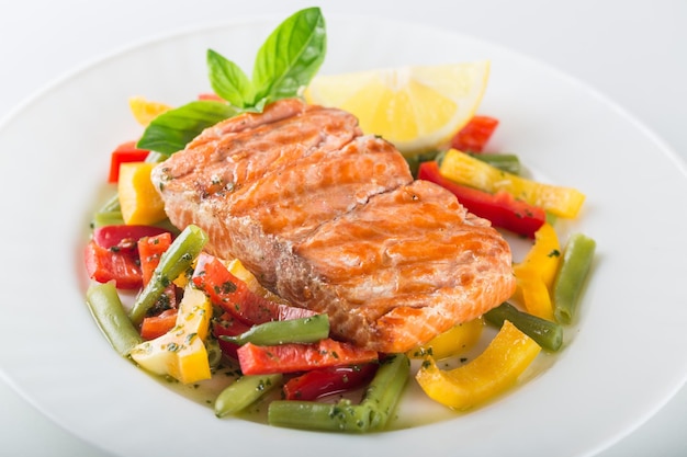 Salmón a la parrilla con verduras en un plato blanco