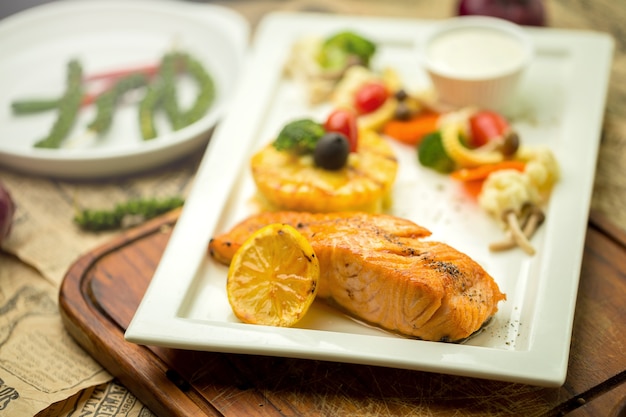 Salmón a la plancha con ajo y hierbas, limón aislado en un plato blanco