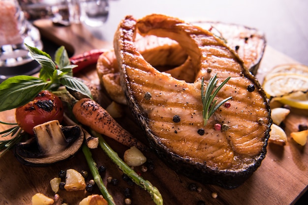 Salmón a la plancha con condimento y diversas verduras en tabla de cortar