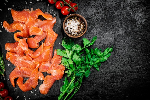 Salmón salado sobre una placa de piedra con tomates y verduras