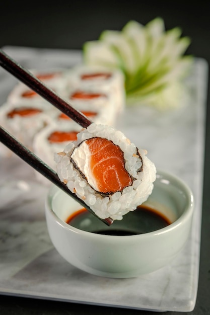 Salmón uramaki en palillos con salsa de soja. De cerca.