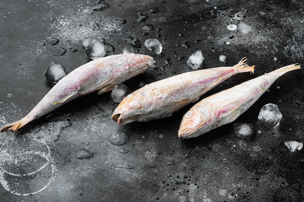 Salmonete congelado o pescado crudo barabulka, sobre fondo de tabla de piedra oscura negra, con espacio para copiar texto