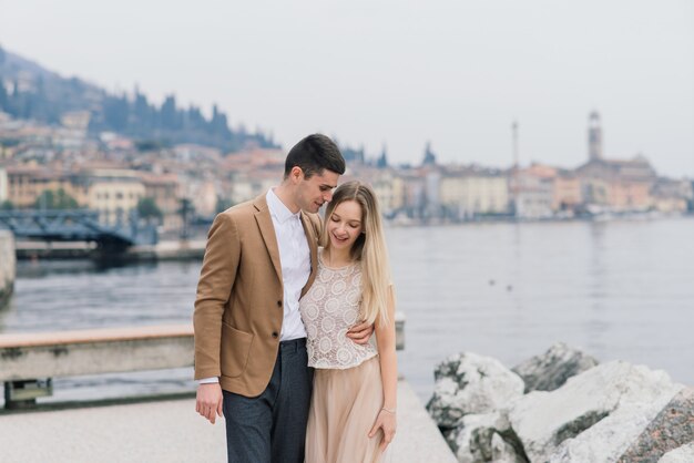 Salo, itália. casal jovem romântico andando na margem do lago, ternura