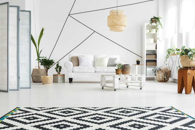 Un salón con alfombra y una planta en la pared.