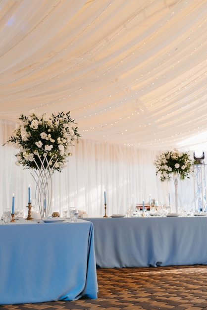 Salón de banquetes en una carpa con manteles y decoraciones azules