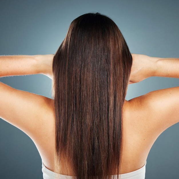 Salón de belleza y modelo de bienestar con textura de cabello liso de champú de queratina brasileño y saludable suave Brillo cosmético y hermosa mujer para el cuidado del cabello en estudio gris con vista posterior