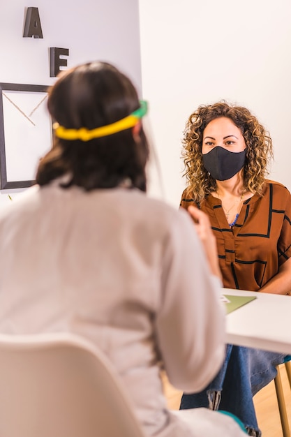 Salón de belleza, reapertura después de la pandemia de coronavirus con medidas de seguridad. Entregar un presupuesto al cliente con una máscara facial. COVID-19