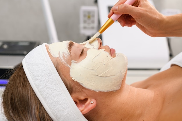 Salón de belleza tratamiento profesional para el cuidado de la piel cosmetóloga aplicar mascarilla peladora de arcilla de alginato facial blanco