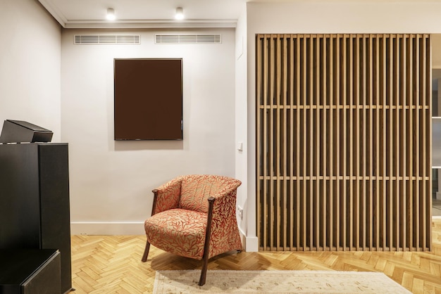 Foto salón de una casa con un sillón de tela roja y una celosía de listones de roble