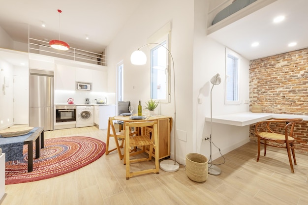 Salón de una casa tipo loft con cocina abierta y un dormitorio en la parte superior amueblado y decorado con cojines estilo marroquí