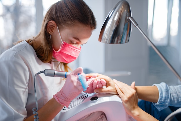 Salón de cosmetología, manicura, manicurista y mujer.