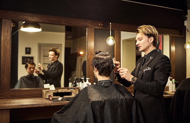 Salón Hombre en una silla de peluquero El peluquero atiende al cliente en la barbería El concepto de cosmetología masculina