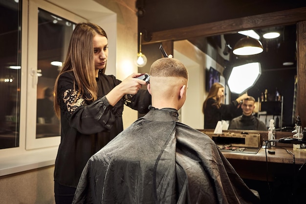 Salón Hombre en una silla de peluquero El peluquero atiende al cliente en la barbería El concepto de cosmetología masculina