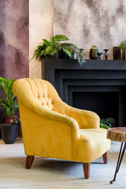 Foto el salón interior. esquina en contraste negro y amarillo, cálidas velas y plantas verdes en una chimenea. lugar para el texto. sillón amarillo habitación cómoda.
