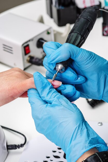 Salón de manicura, manos del cliente y primer plano maestro. Tratamiento de uñas con cortador.