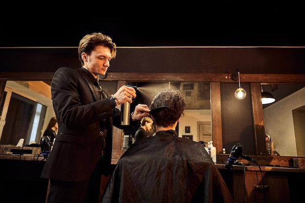 Salon Mann in einem Friseurstuhl Der Friseur bedient den Kunden im Friseursalon Das Konzept der männlichen Kosmetologie