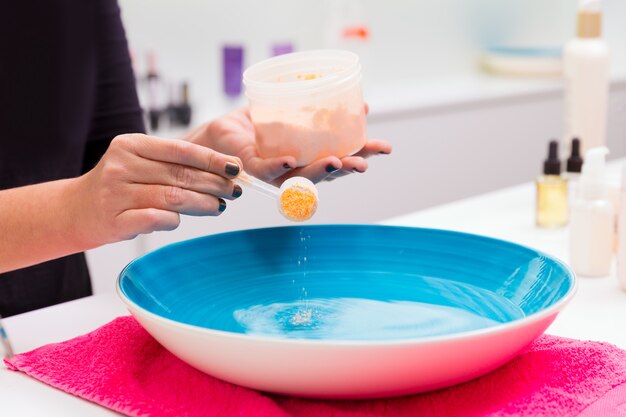 Foto salón de uñas que prepara un baño exfoliante para la renovación de la piel.