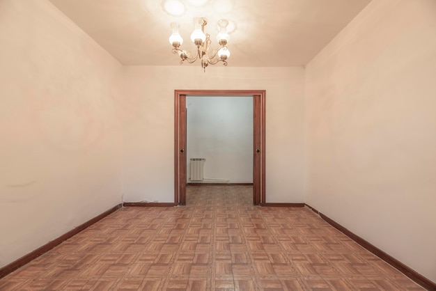 Salón vacío con puertas correderas de madera oscura y suelo de sintasol imitación madera