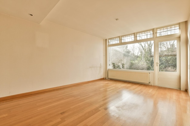 Un salón vacío con suelos de madera y una ventana.