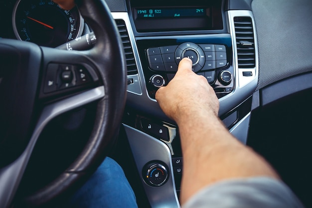 Salpicadero de coche. Primer plano de radio. El hombre pone radio