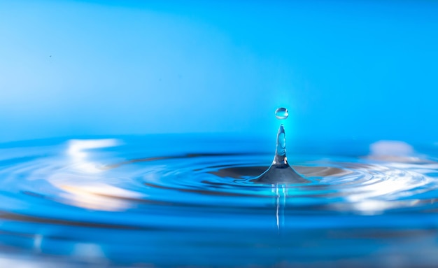 Salpicadura de agua gota de agua salpicadura de las gotas de agua que caen sobre un fondo azul