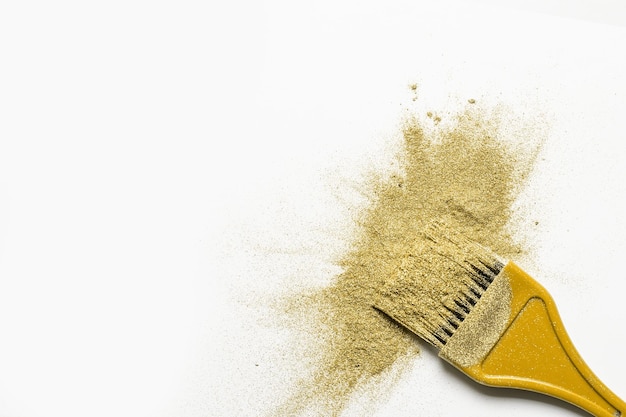 Salpicadura de polvo fino dorado y pincel para maquillador o diseño gráfico en fondo blanco