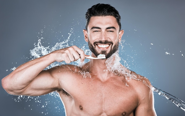 Salpicaduras de agua cepillarse los dientes y retrato de hombre con cepillo de dientes bienestar dental y cuidado de la boca saludable Modelo masculino feliz limpieza oral y aliento fresco para la felicidad de la sonrisa y cosméticos de ducha