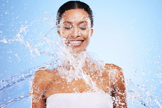 Salpicaduras de agua mujer negra y belleza sobre fondo azul cuidado de la piel hidratación y bienestar facial cuidado corporal y ducha limpieza e higiene personal Modelo de estudio joven gota de agua y dermatología