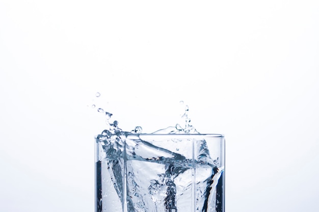 Salpicaduras de agua en un vaso de un cubo de hielo.