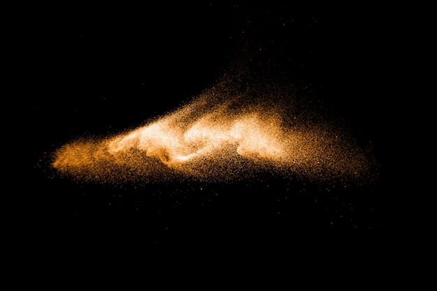 Salpicaduras de arena de color marrón. Explosión de arena de río seco aislada sobre fondo negro. Nube de arena abstracta.