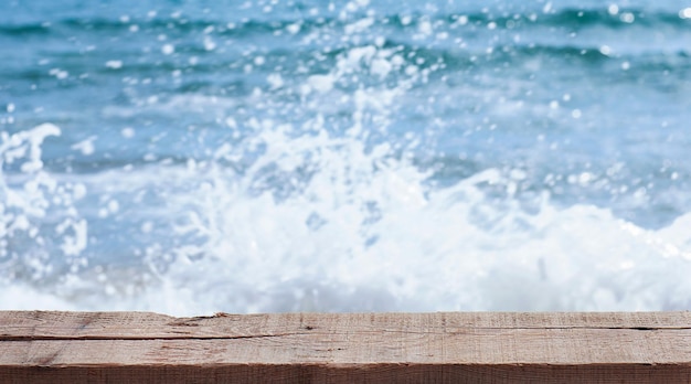 las salpicaduras borrosas de las olas del mar detrás de la superficie de madera libre. soporte de madera para productos