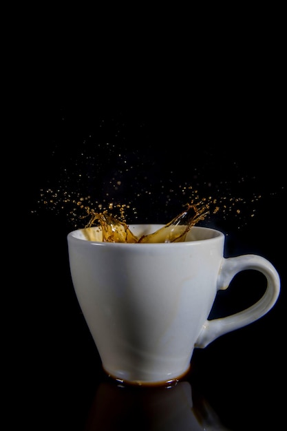 Salpicaduras de café en una taza blanca sobre un fondo negro