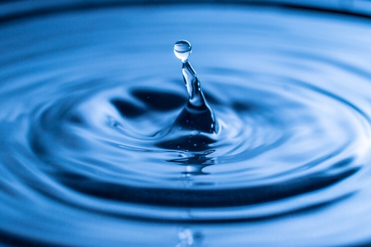 Salpicaduras de gota de agua en un vaso de color azul