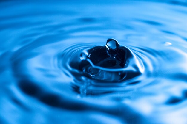 Salpicaduras de gota de agua en un vaso de color azul