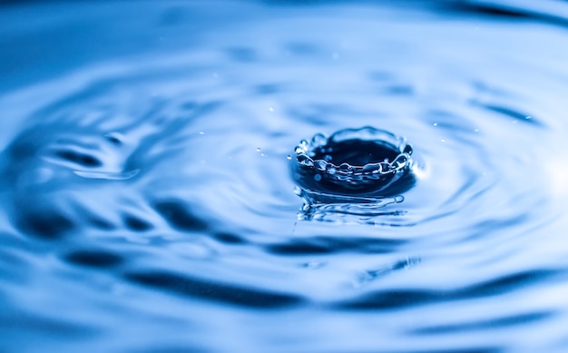 Salpicaduras de gota de agua en un vaso de color azul