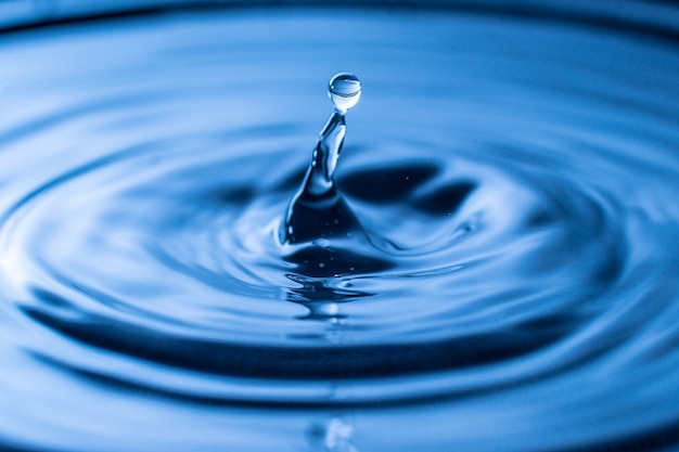 Salpicaduras de gota de agua en un vaso de color azul