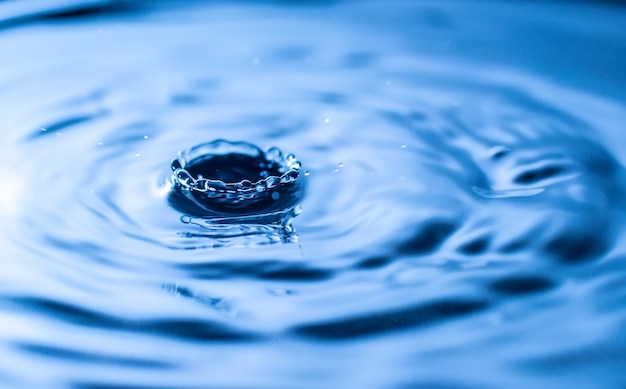 Salpicaduras de gota de agua en un vaso de color azul