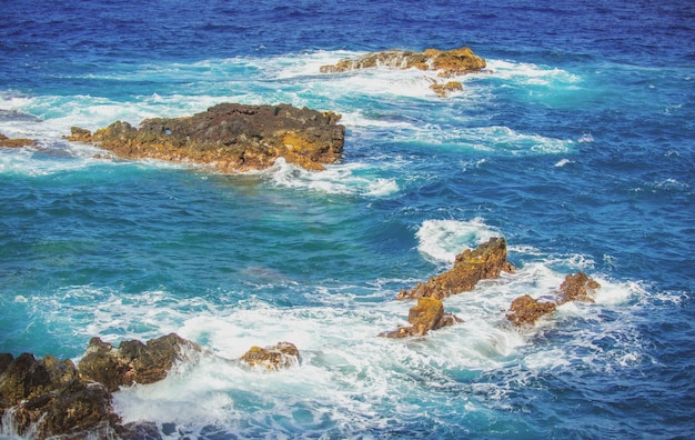 Salpicaduras de olas en la roca en el mar ola golpeó la piedra en el océano con un fondo de agua