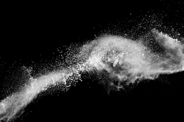 Foto salpicaduras de partículas de polvo blanco. el movimiento freez de talco estalló en un fondo oscuro.