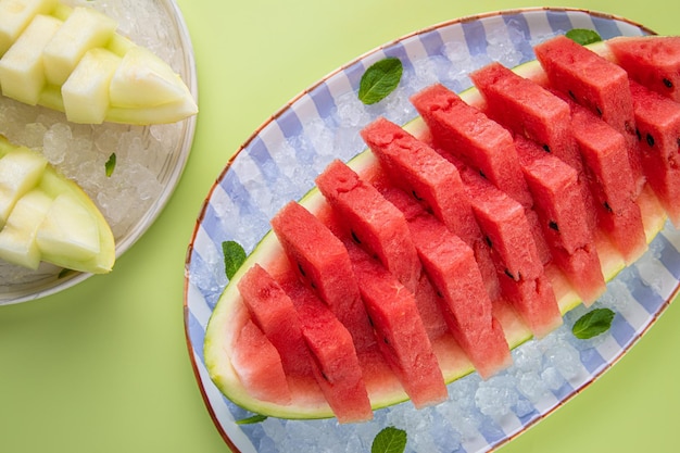 Salpicaduras de sandía y agua aisladas sobre fondo verde pastel Fruta mínima