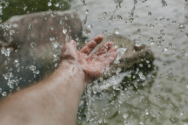 Salpicos de água caindo de uma cachoeira na mão de um homem