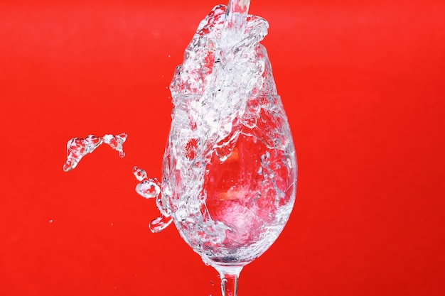 Salpicos de água em uma taça de vinho em fundo vermelho, vista lateral