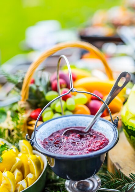 Salsa de arándanos en la mesa llena de frutas frescas. Catering al aire libre.